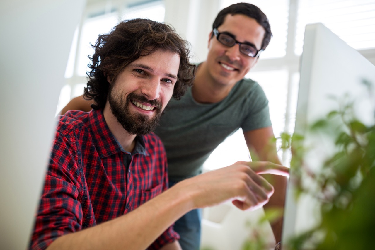 Two male graphic designers interacting over computer